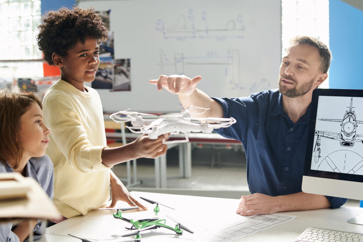 Aeromodeling class teacher explaining to schoolkid how quadcopters fly