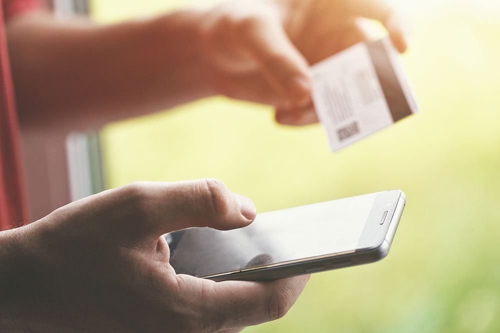 photo of a person holding a credit card and a cell phone in his hands.